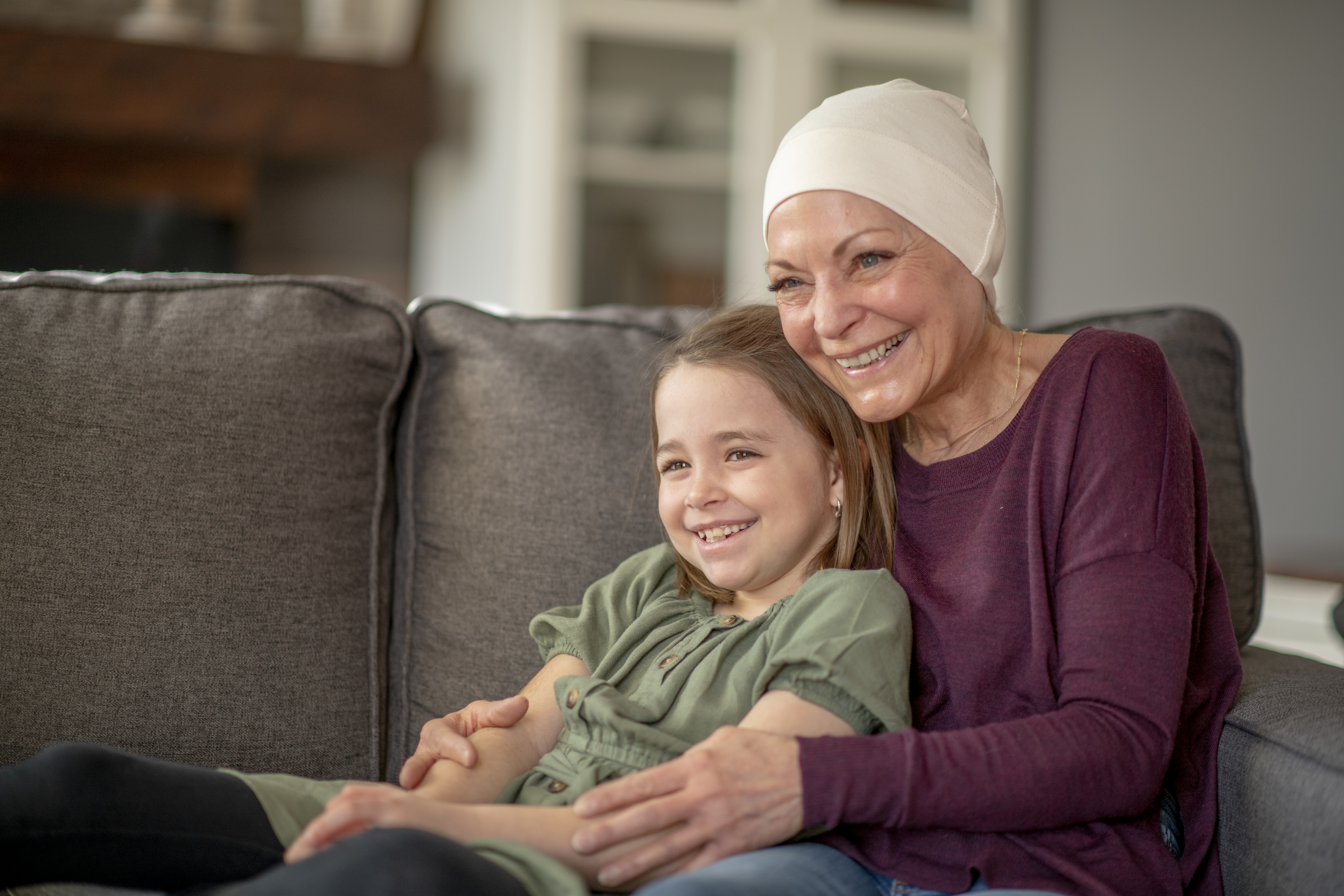 Grandmother with her dauther sitting on a couch. They are hugging